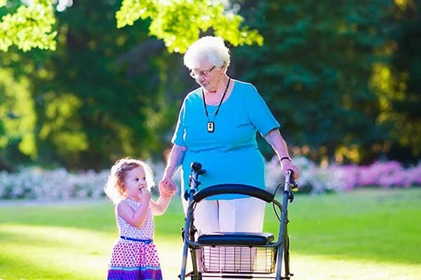 Elderly woman with mobile medical alert walking with grand daughter