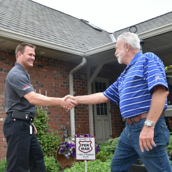 Technician shaking hands with home security customer